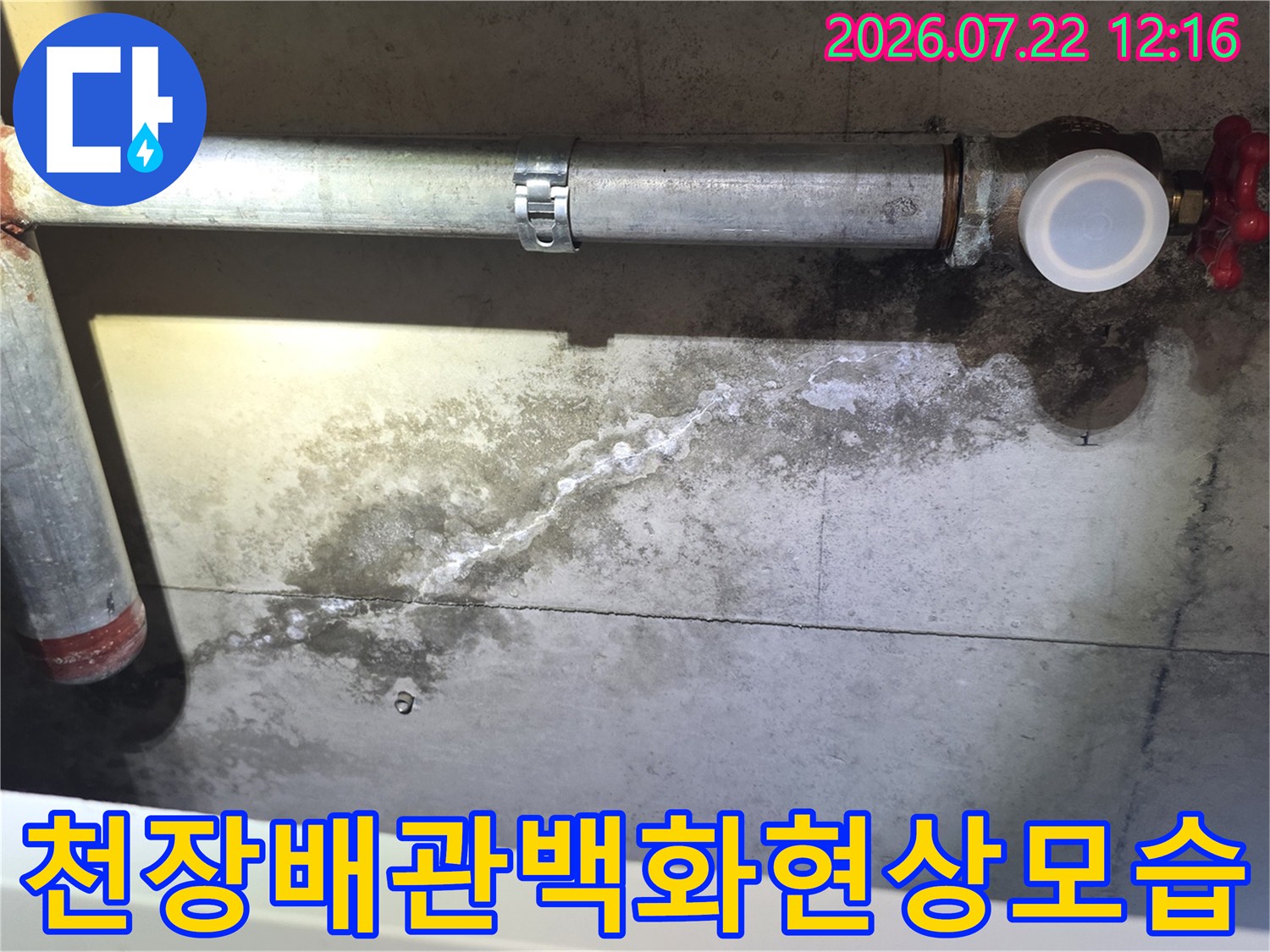 회색 콘크리트 천장에 하얀 누수 자국과 금속 배관이 설치된 모습