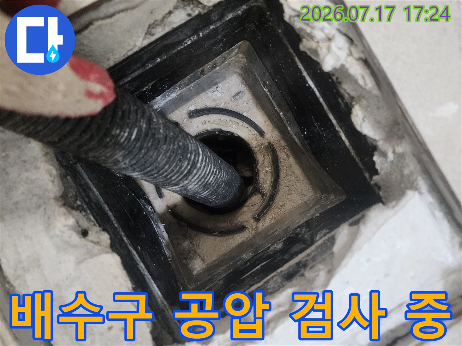 화장실 배수구 내부로 연결된 공압 테스트용 호스를 삽입하여 점검하는 모습