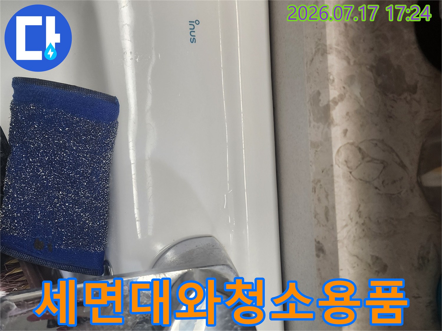 흰색 세면대 위에 놓인 파란색 수세미와 수도꼭지