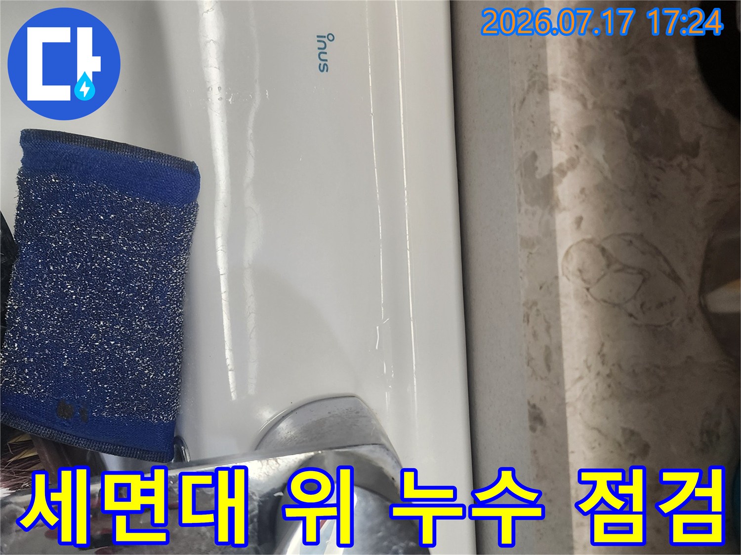 흰색 세면대 위에 놓인 파란색 스펀지와 수전 부위의 정밀 점검 장면