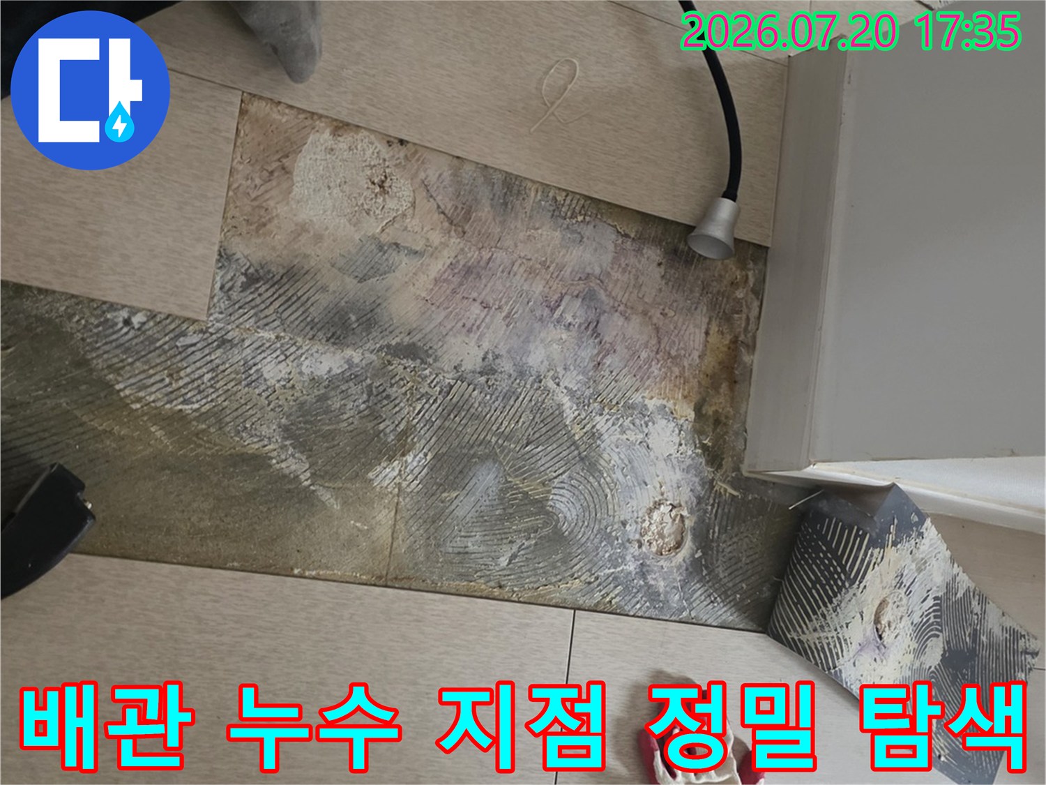 거실 바닥면 위에서 전문 장비를 사용하여 매립 배관의 파손 위치를 세심하게 추적하는 모습입니다.