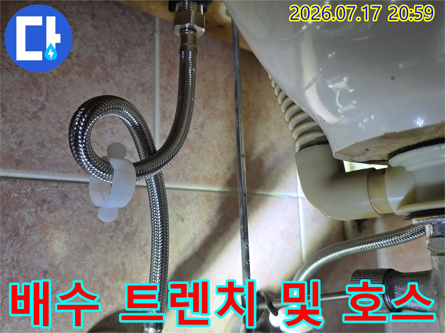 싱크대 하단부에 노출된 배수용 주름관의 연결 상태를 정밀 점검하는 사진