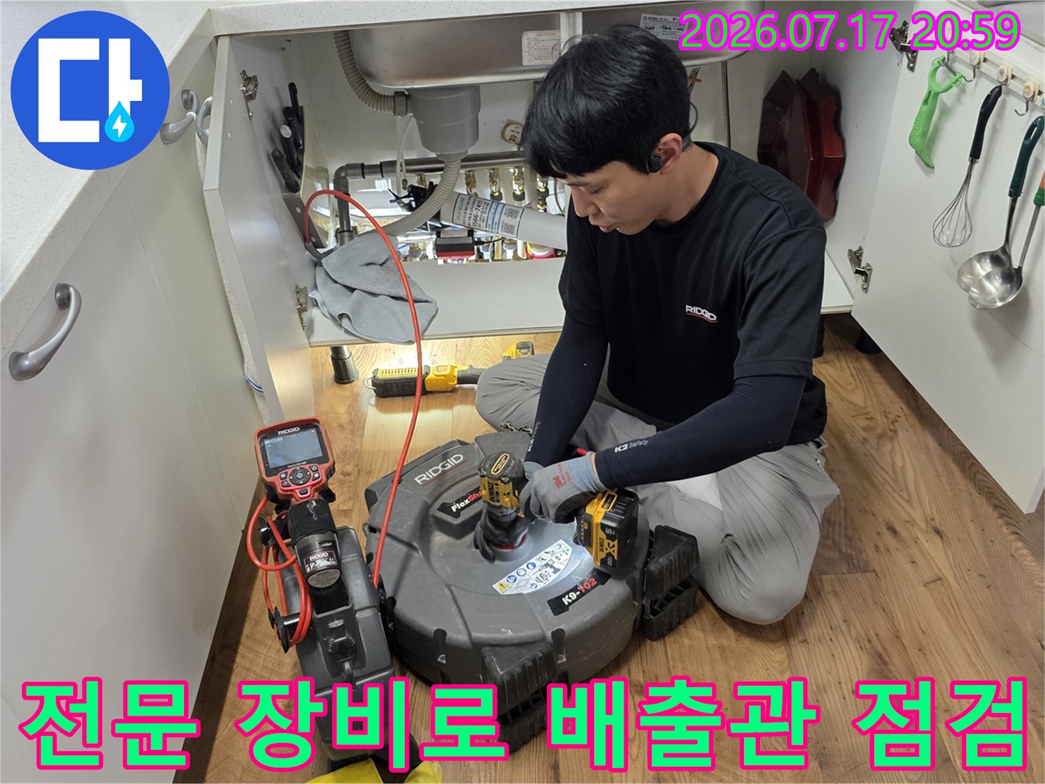 싱크대 하부 공간에서 정밀 탐지기를 조작하며 배수 경로를 분석하는 장면