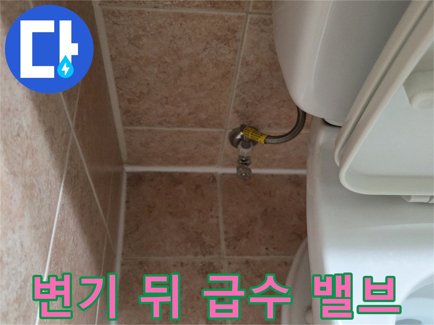화장실 변기 뒤편에 위치한 수도 급수 밸브와 타일 벽면 모습