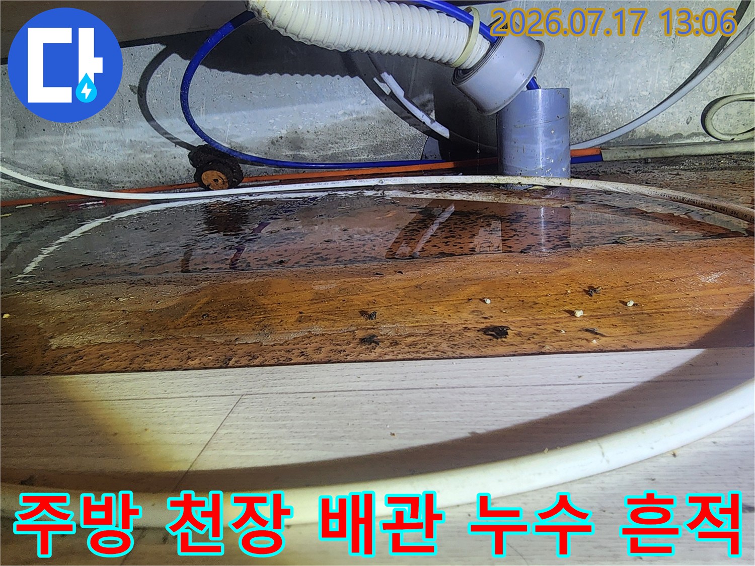 주방 천장 하부의 목재 자재가 물에 젖어 변색된 모습과 연결된 배관들
