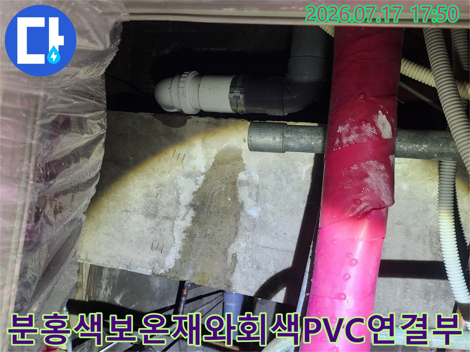 천장 내부의 분홍색 보온재 배관과 그 아래로 연결된 회색 PVC 배수관-누수 유출 지점