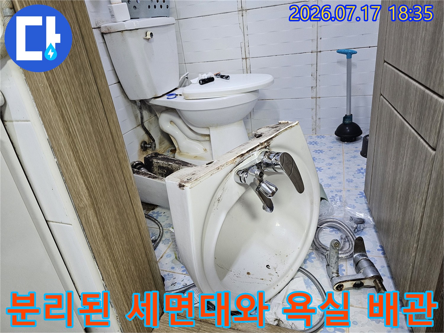 흰색 도기 세면대가 바닥에 놓여 있고-뒤편으로 변기와 수도 밸브가 보임