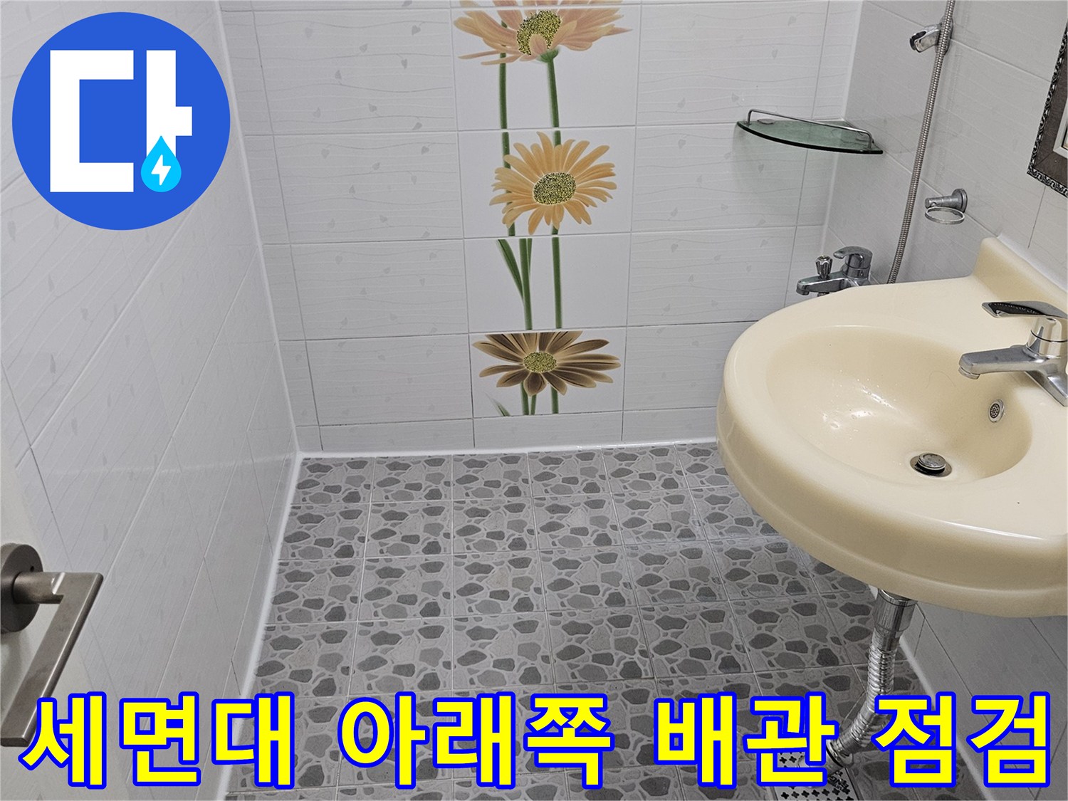 하얀색 세면대-배관 연결 부위와 주변 타일 벽면 사진