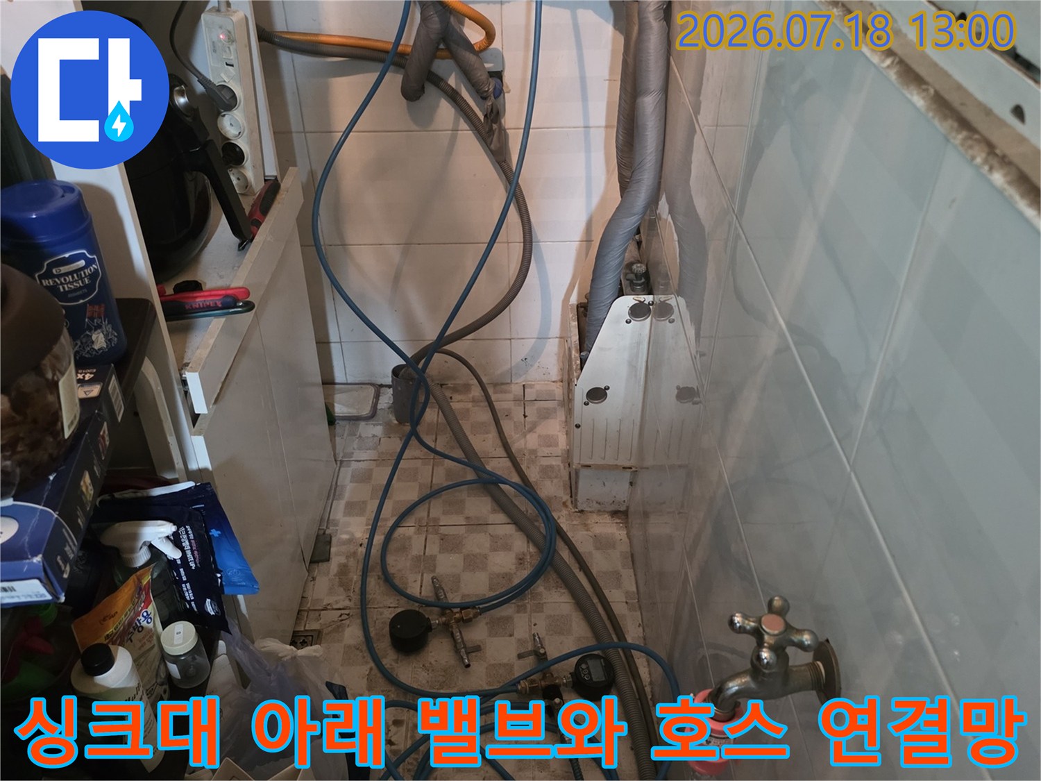 벽면에 고정된 두 개의 수도 밸브와 여기서 뻗어 나온 파란색 급수 호스들