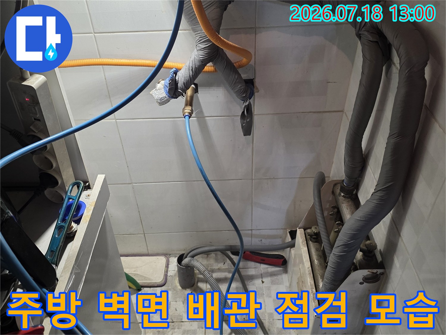 흰색 타일 벽면에 설치된 회색 보온재 배관과 파란색 탐지 호스-누수 지점 확인 과정