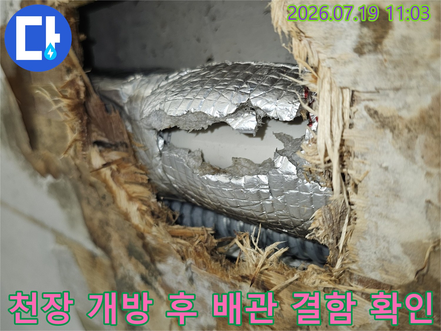 젖어서 색이 변한 단열재와 훼손된 은색 배관 보온재가 노출된 주방 천장 내부 모습