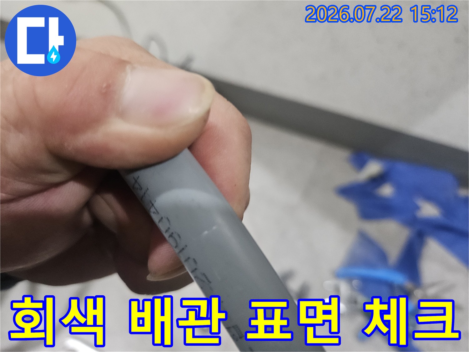 누수가 발생한 현장의 회색 플라스틱 배관을 손으로 잡고 세밀하게 관찰하는 장면-원인 분석
