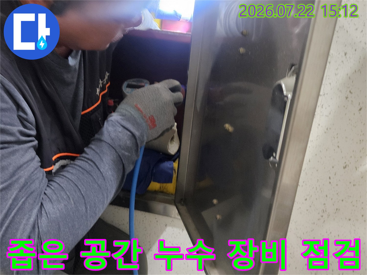 스테인리스 마감재 아래 좁은 틈새로 손을 넣어 탐지 장비를 조작하는 엔지니어의 모습