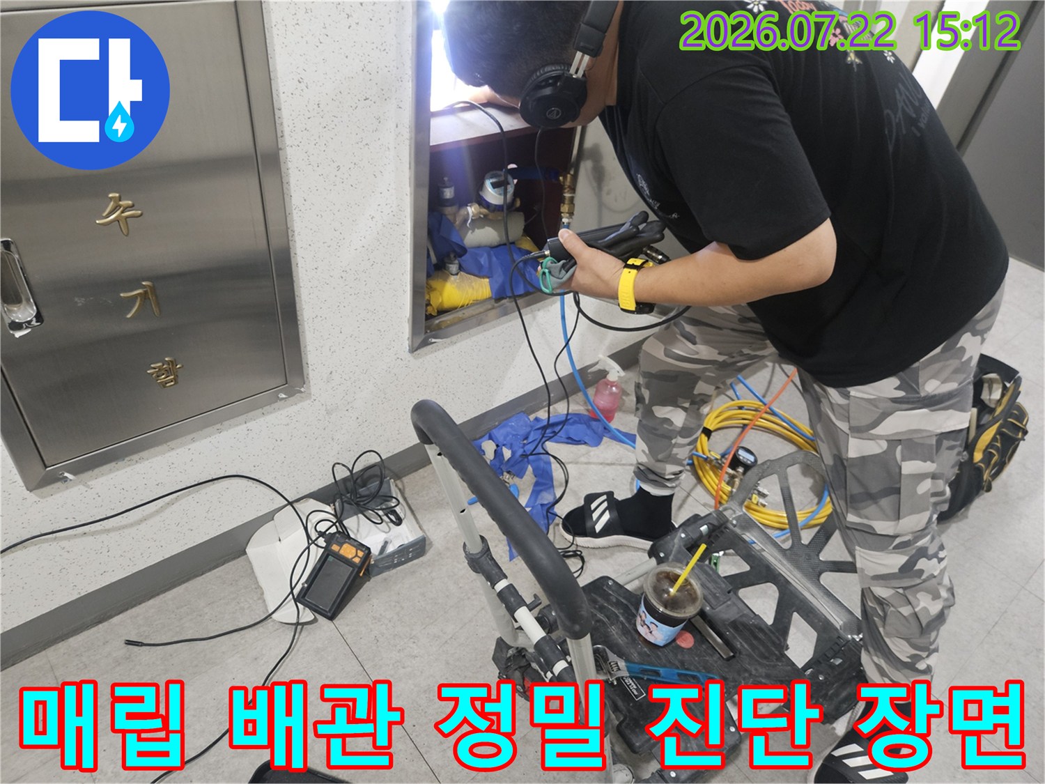 작업자가 벽면 함 내부의 배관 상태를 점검하며 가스 누출 탐지기를 조작하는 사진