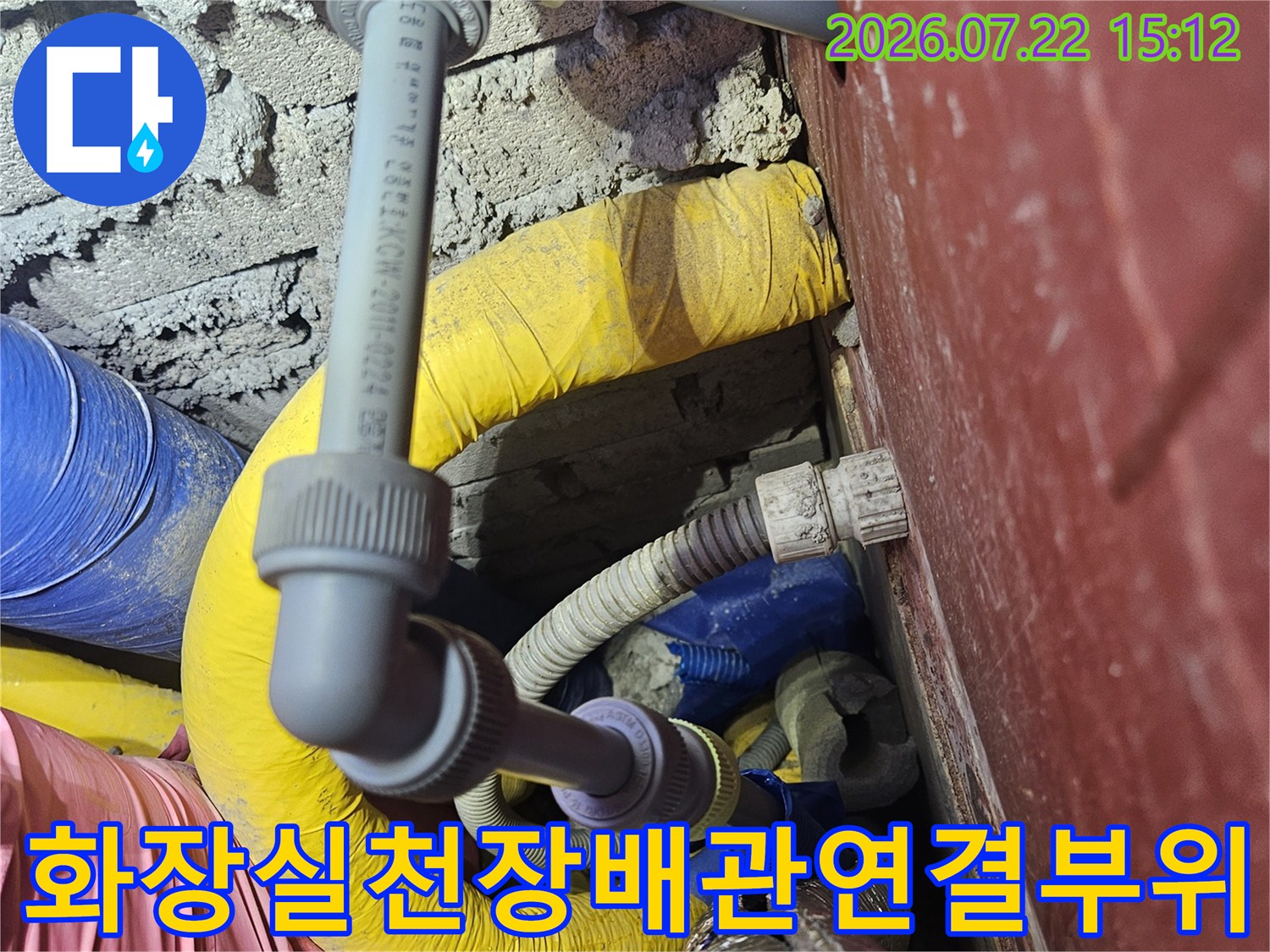 화장실-천장-내부에-복잡하게-얽혀있는-회색-플라스틱-배관과-노란색-보온재-모습