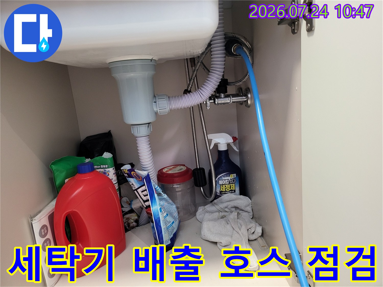 세탁기 하부의 회색/흰색 파이프 연결부와 공압 검사용 장비가 결합된 모습