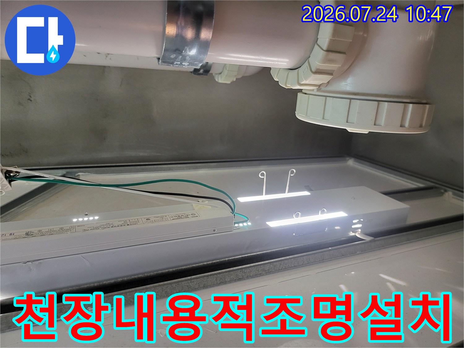 화장실 천장 내 배출 파이프와 연결부위를 조명으로 비추며 정밀하게 점검하는 모습