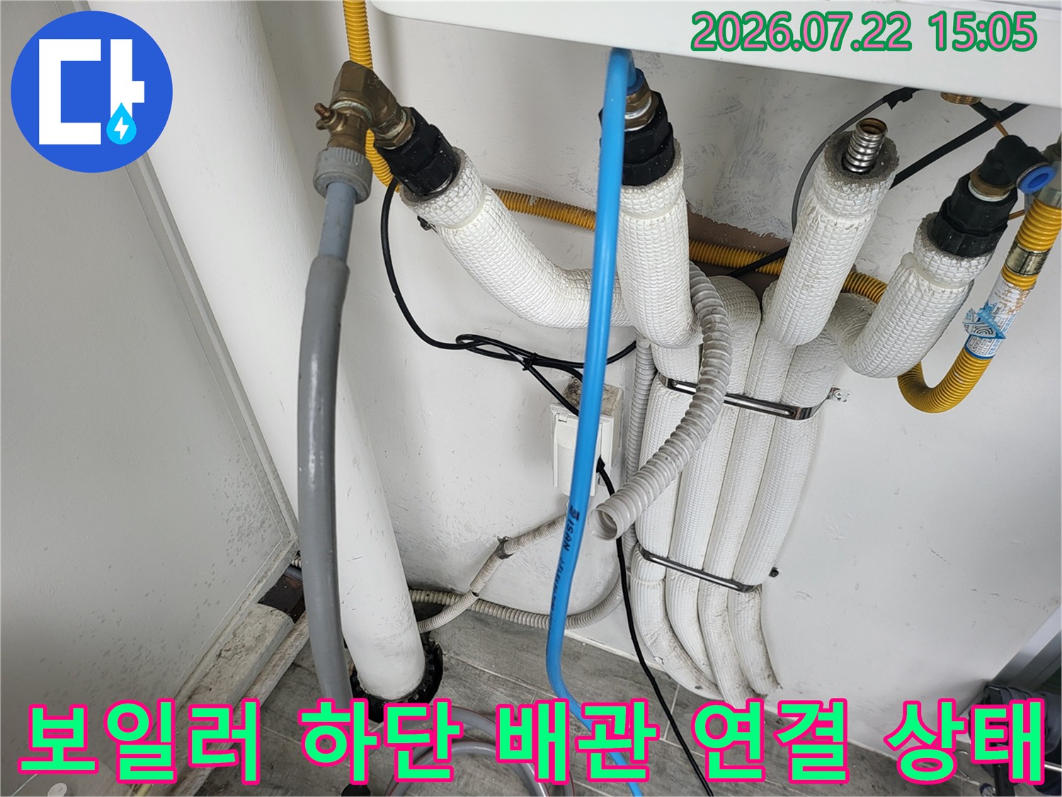 흰색 보온재로 감싸진 보일러 하단의 여러 가닥 배관-연결 부속과 밸브 모습
