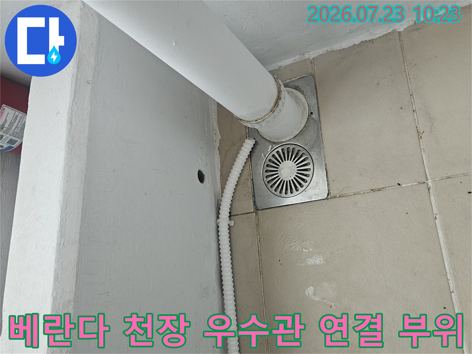 아파트 베란다 천장에 설치된 흰색 우수관과 금속제 마감재-배관 연결부 모습