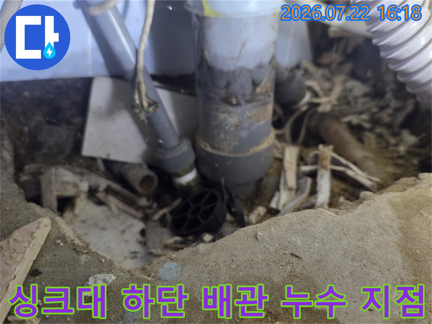 주방 싱크대 아래쪽-오염된 바닥과 복잡하게 얽힌 배관 연결 부위 모습