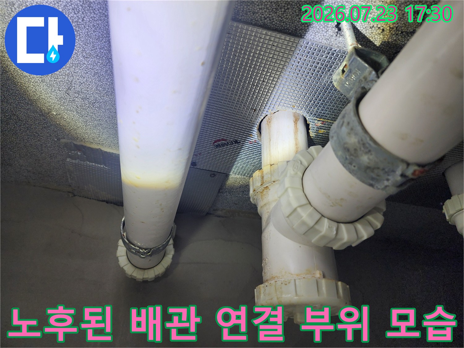 천장에-고정된-흰색-플라스틱-배관과-금속-클램프-그리고-연결-캡-부분