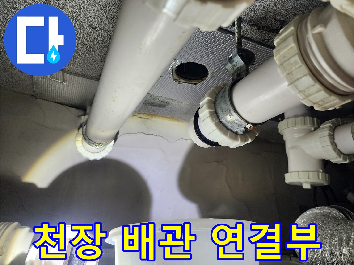 화장실 천장 내부의 흰색 PVC 배관과 연결 소켓 부위를 근접 촬영하였습니다.