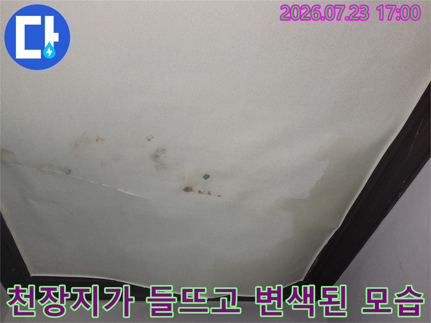 아랫집 거실 천장의 벽지가 물에 젖어 들뜨고 갈색 얼룩이 생긴 상태
