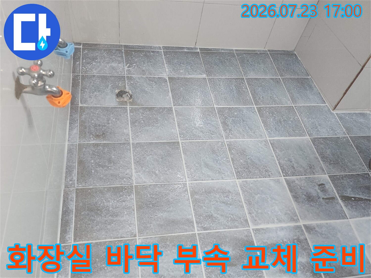 회색 타일 벽면 앞에 놓인 파란색과 주황색 캡이 씌워진 신규 배관 부속들