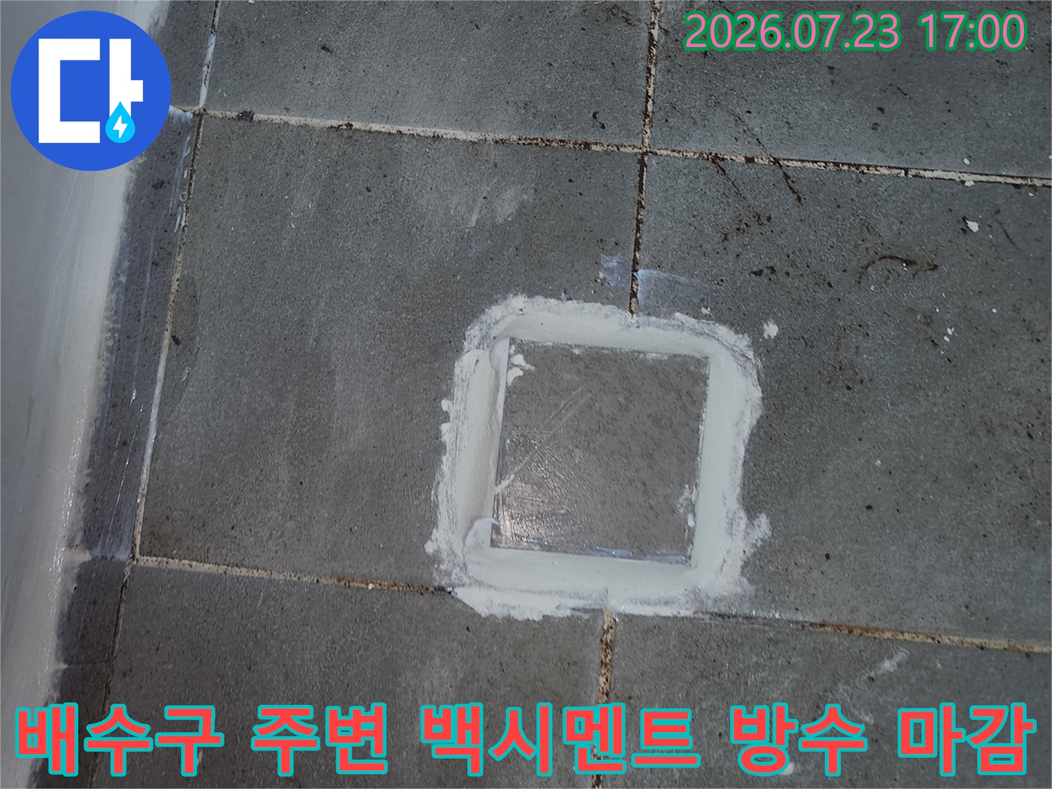 회색빛 욕실 타일 중앙의 배수 트랩 주위에 하얀 방수재가 충진된 상태