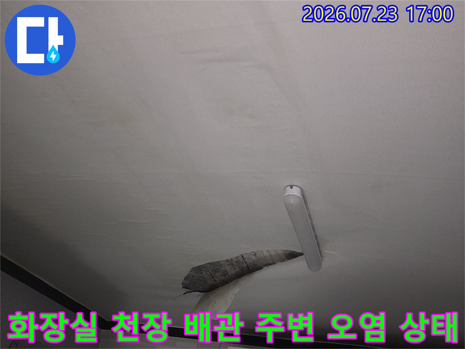 흰색 욕실 천장의 점검구 부근에서 발생한 어두운 색상의 누수 흔적과 얼룩
