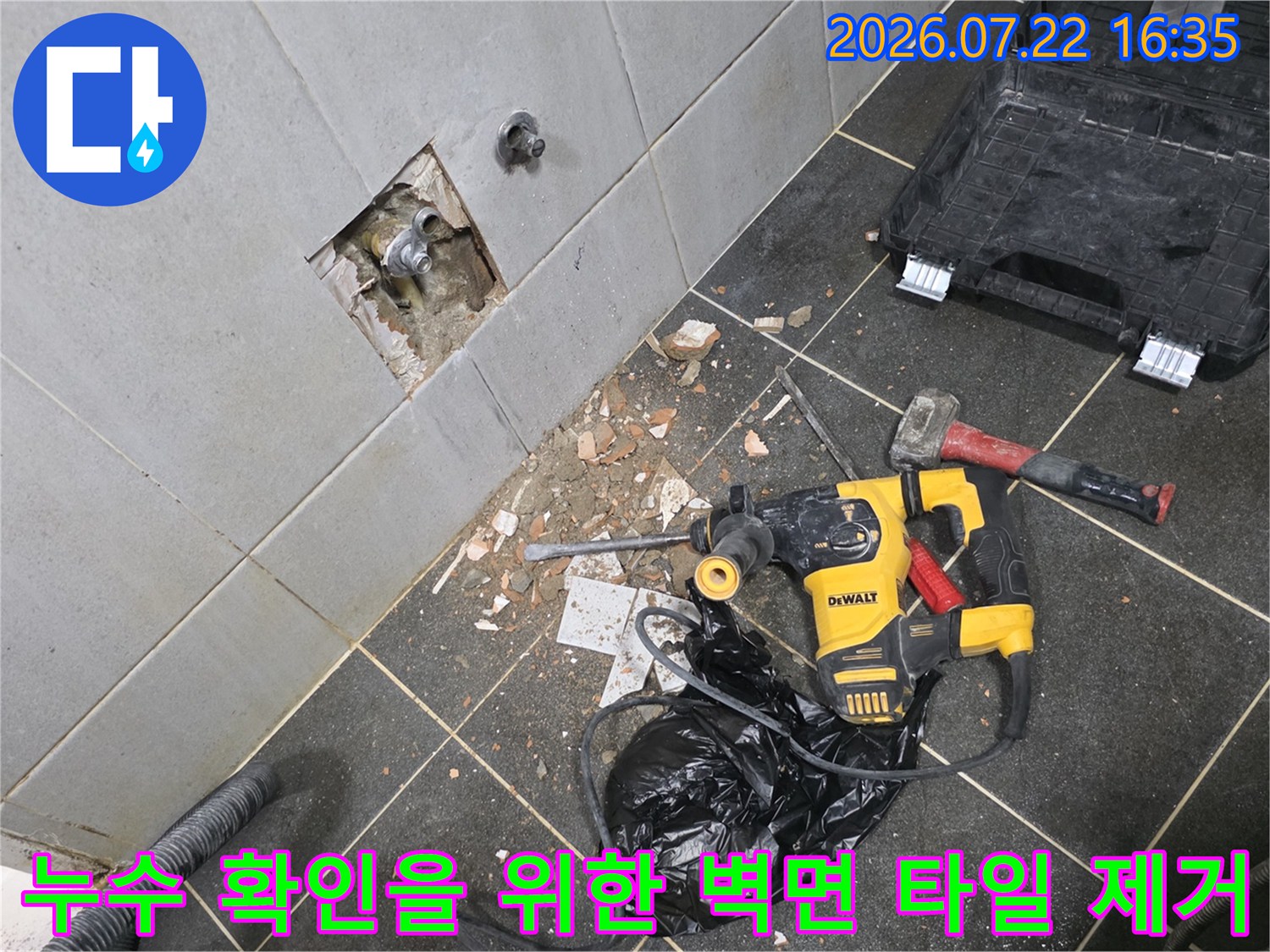 굴착된 타일 벽면 아래로 전동 드릴과 장비들이 놓여 있는 누수 공사 현장 사진