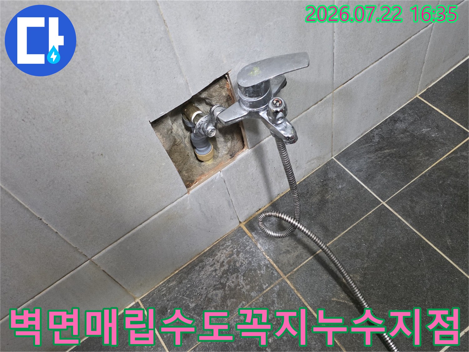 타일 벽면에 설치된 수도꼭지와 그 주변의 배관 연결 부위가 노출된 모습