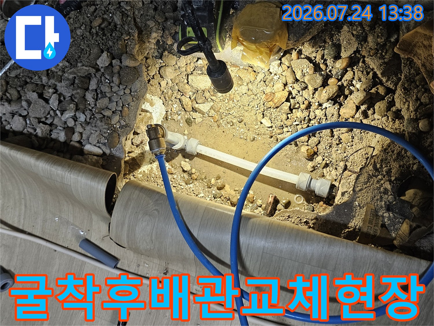 바닥을 굴착하여 노후된 배관을 새 제품으로 교체하고 파란색 공압 테스트 호스를 연결한 모습
