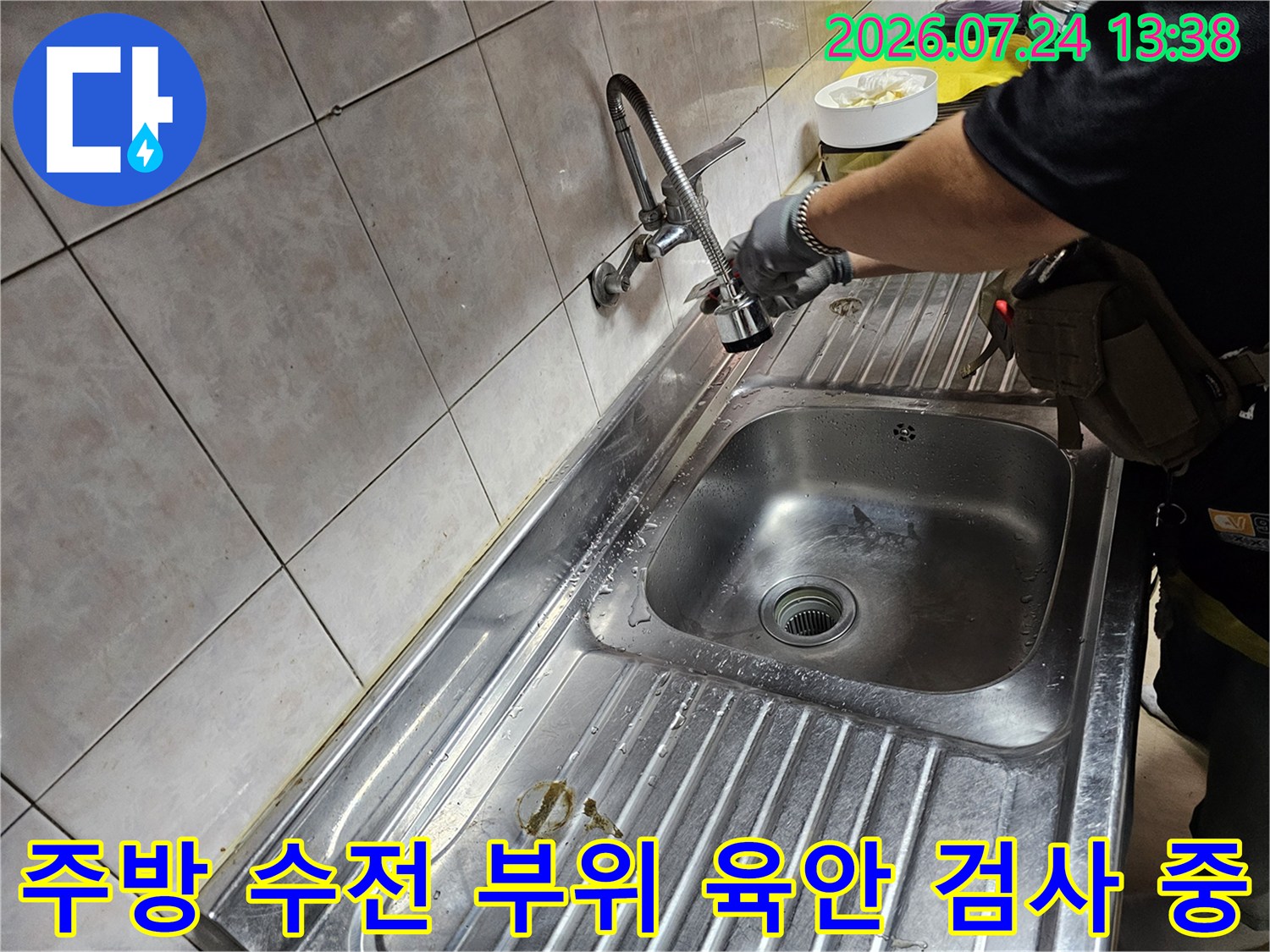 스텐리스 소재의 싱크대 볼과 수전 주변을 점검하고 있는 엔지니어의 손길