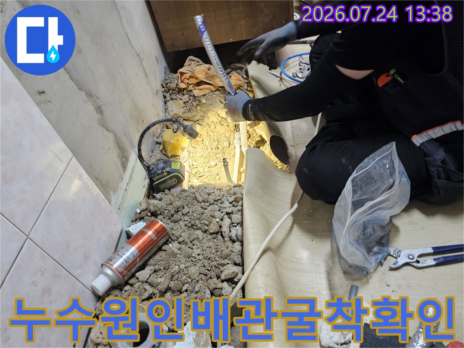 작업자가 좁은 굴착 구역 안에서 파란색 보온재가 씌워진 수도 배관을 세밀하게 살피는 모습