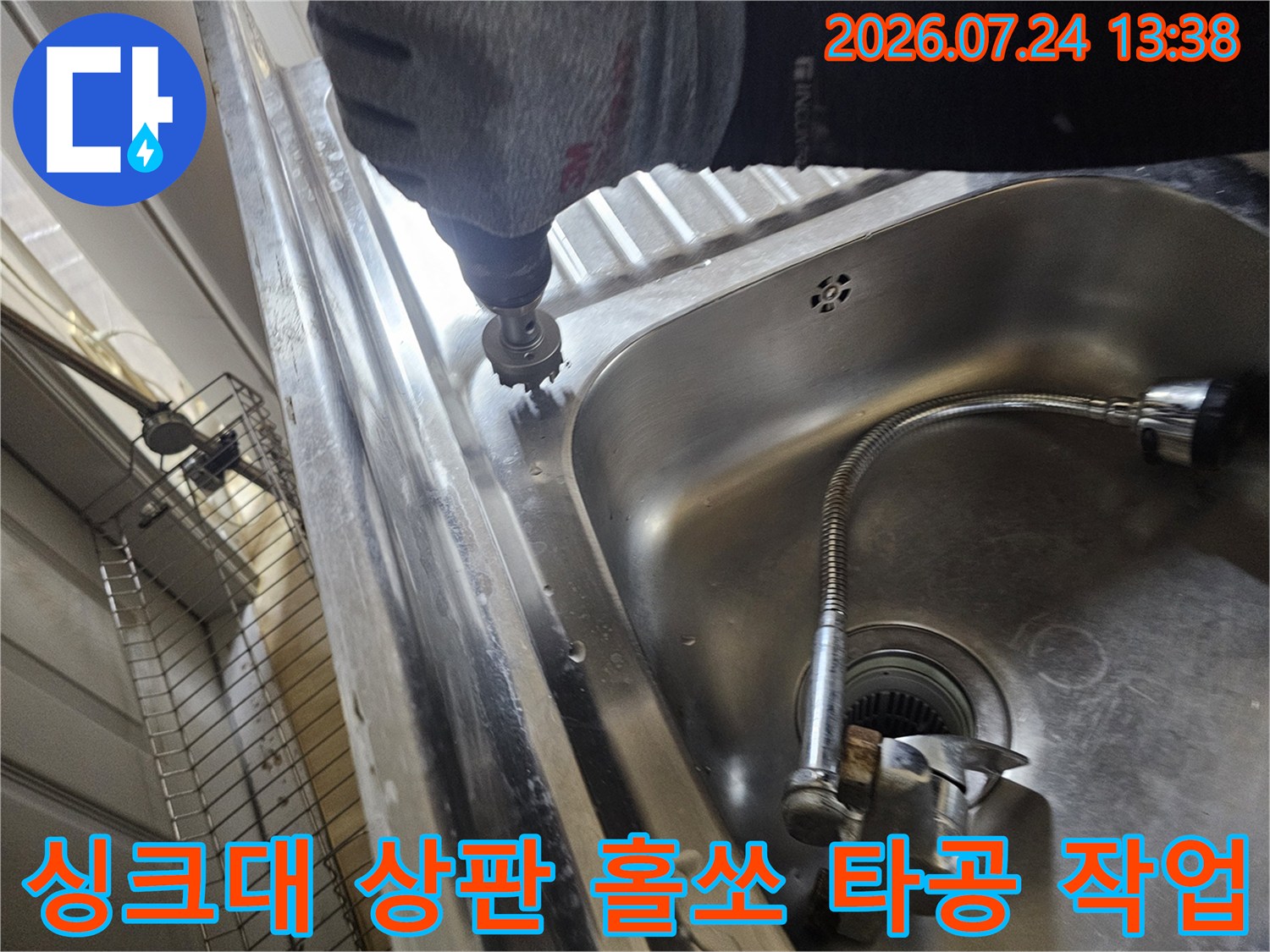 회색 장갑을 낀 작업자가 전동 드릴과 홀쏘를 이용해 싱크대 스테인리스 상판 가장자리를 타공하는 모습