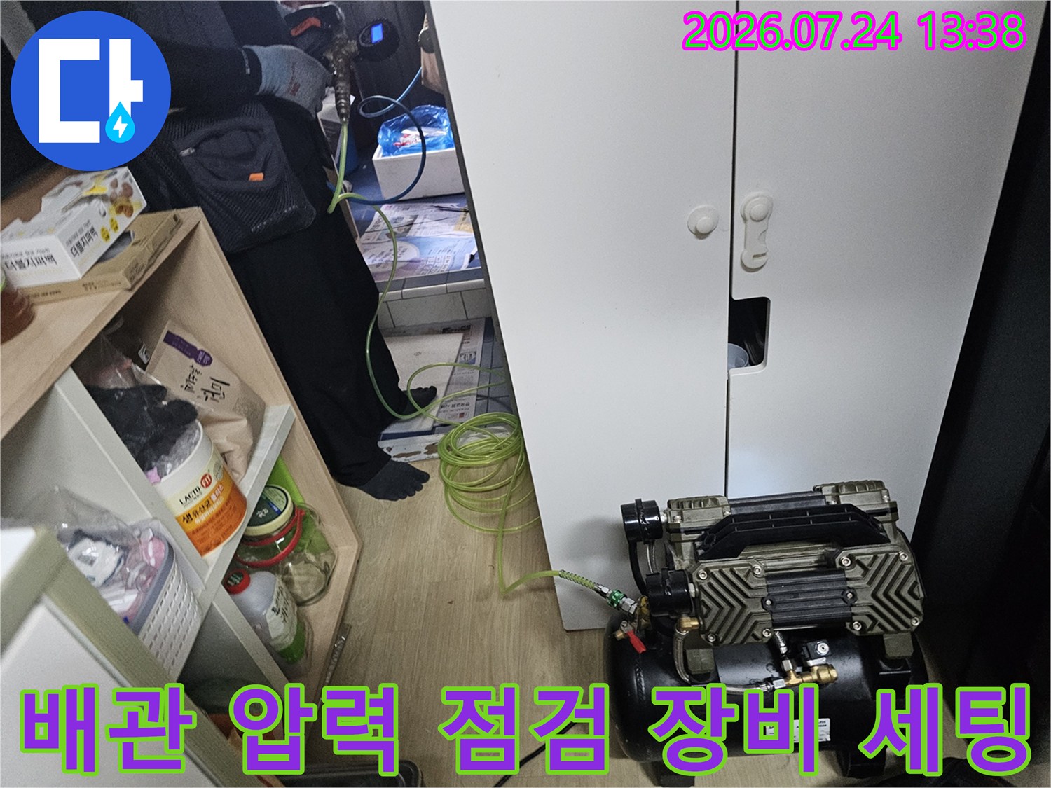 흰색 수납장 앞에 배치된 누수 탐지용 펌프-연결 호스가 배관으로 이어짐