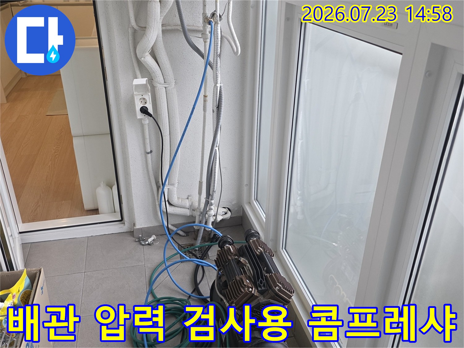 흰색 벽면 배관 옆으로 연결된 파란색 호스와 누수 진단 장비