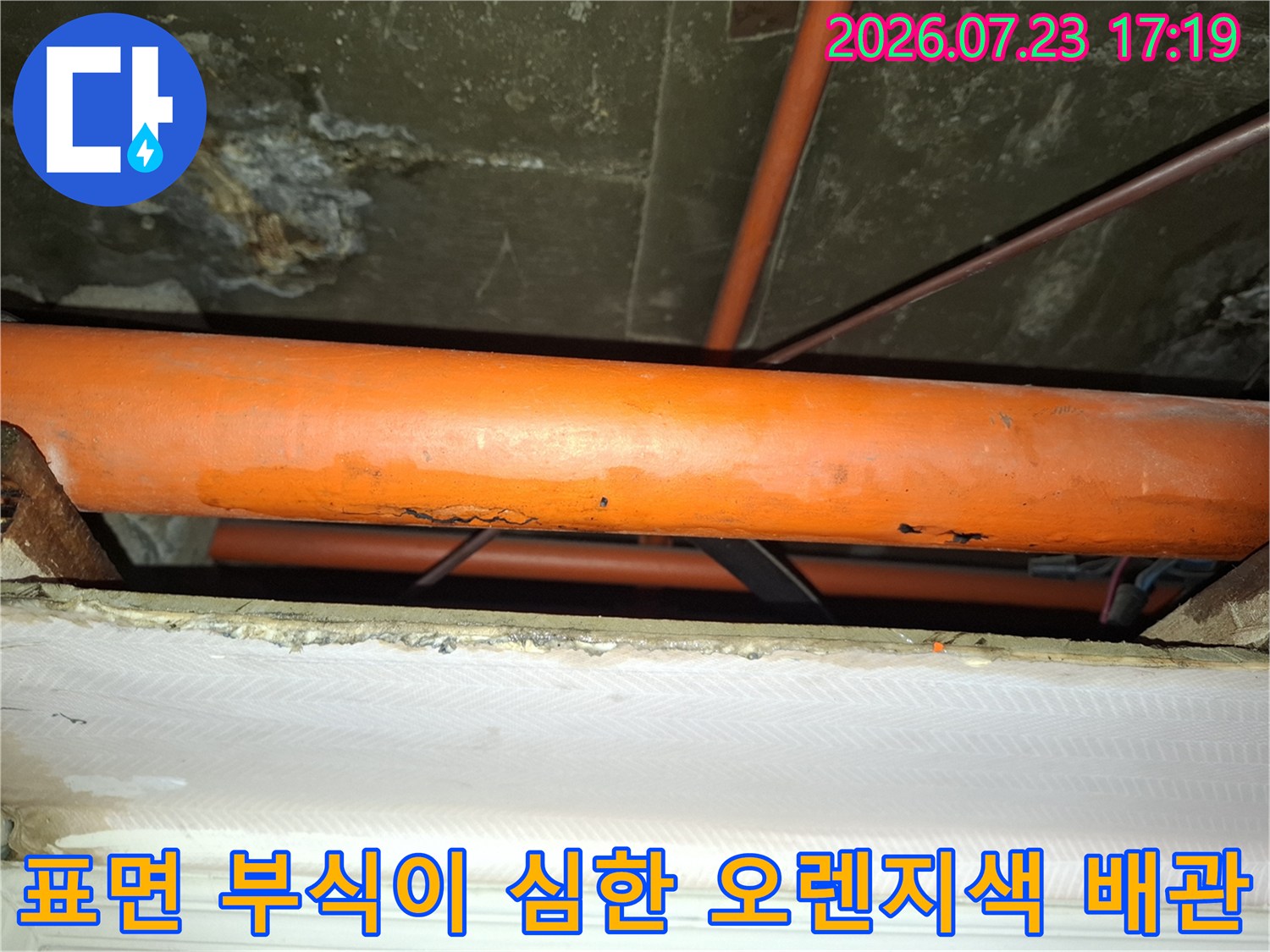 오렌지색 배관의 외벽이 삭아 누수가 발생한 지점을 촬영한 사진-노후 배관 상태 확인