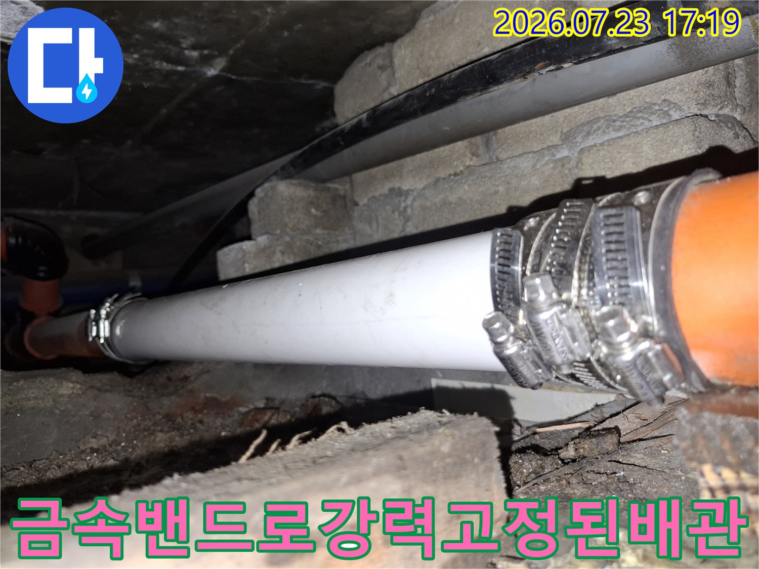 흰색 배관과 주황색 배관의 연결 부위에 금속제 호스 밴드가 촘촘하게 체결된 모습