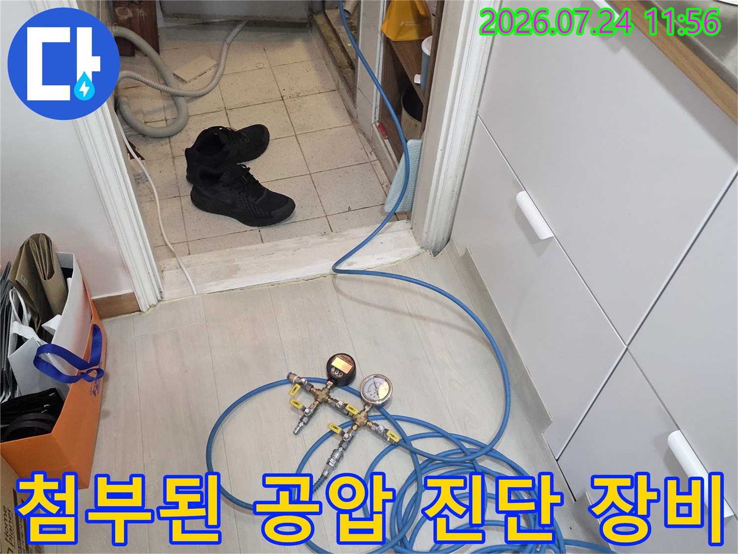 파란색 호스와 압력 게이지로 배관의 누수 여부를 정밀히 모니터링하는 기술적인 작업 단계입니다.