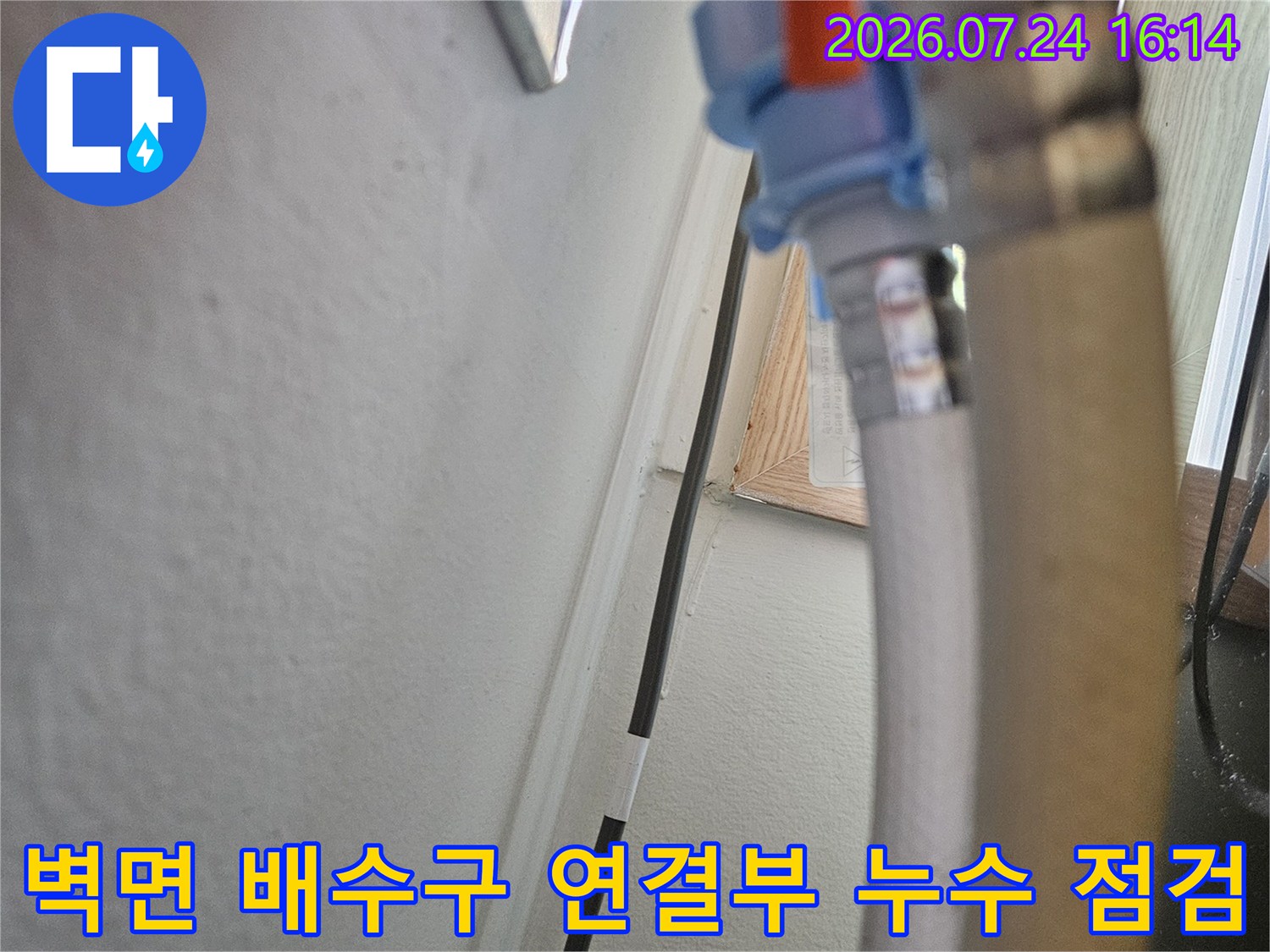 싱크대 하부의 오렌지색 배관과 벽면 연결 부위 확대 사진