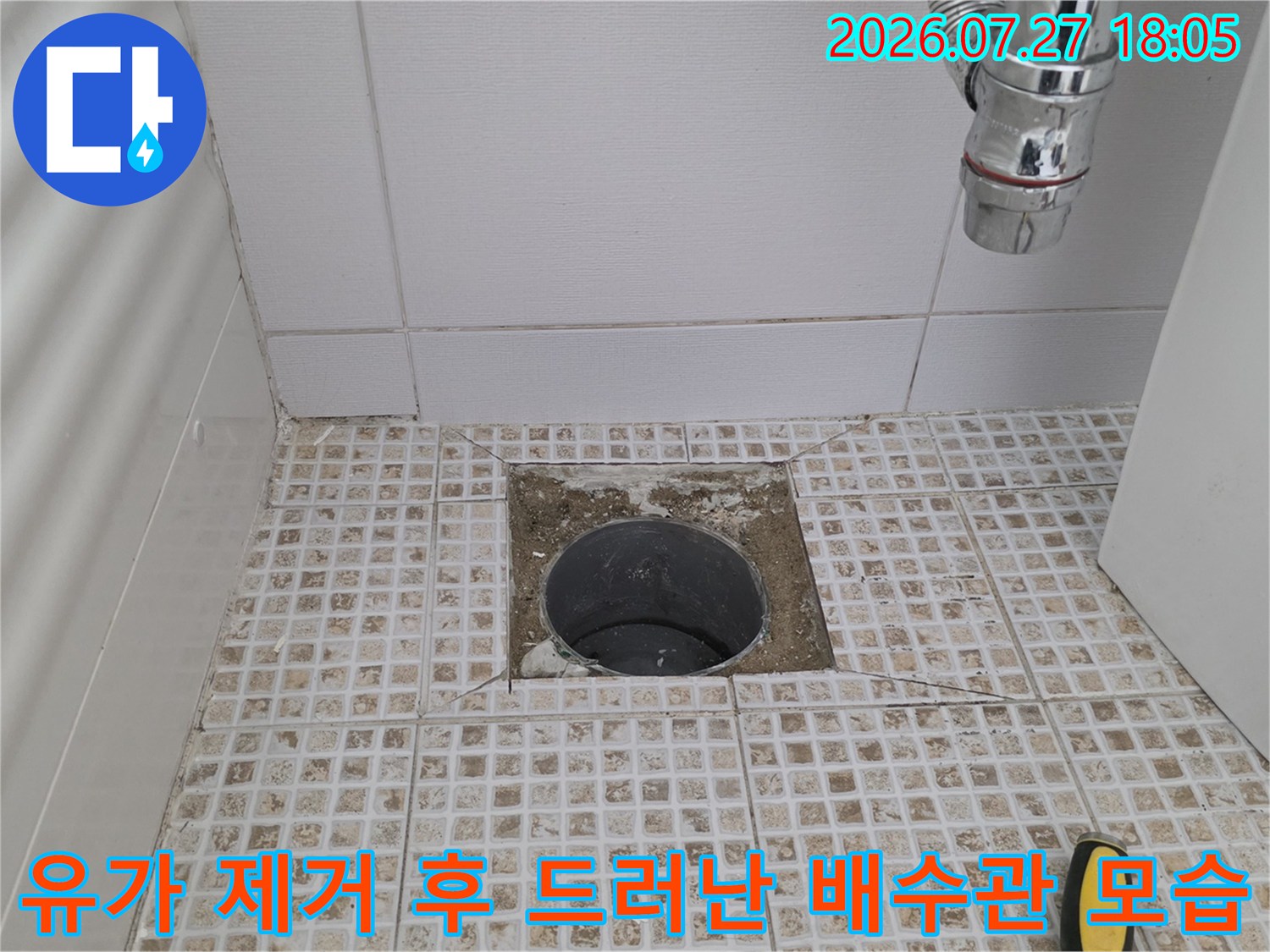 욕실 바닥의-배수구 주변 마감재를 제거하여 배관 입구가 노출된 사진