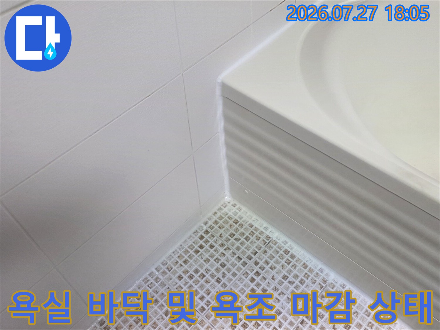 하얀색 모자이크 타일 바닥과 물결무늬 욕조 패널-접합 부위 근접 촬영