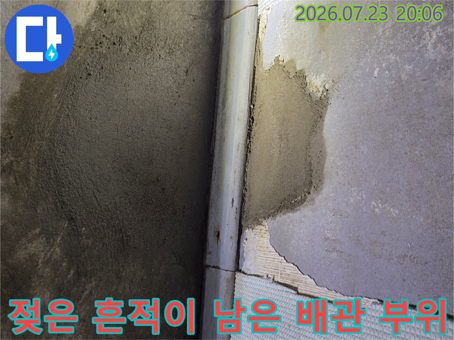 물기 어린 벽면과 파손된 타일 사이의 배관 연결부