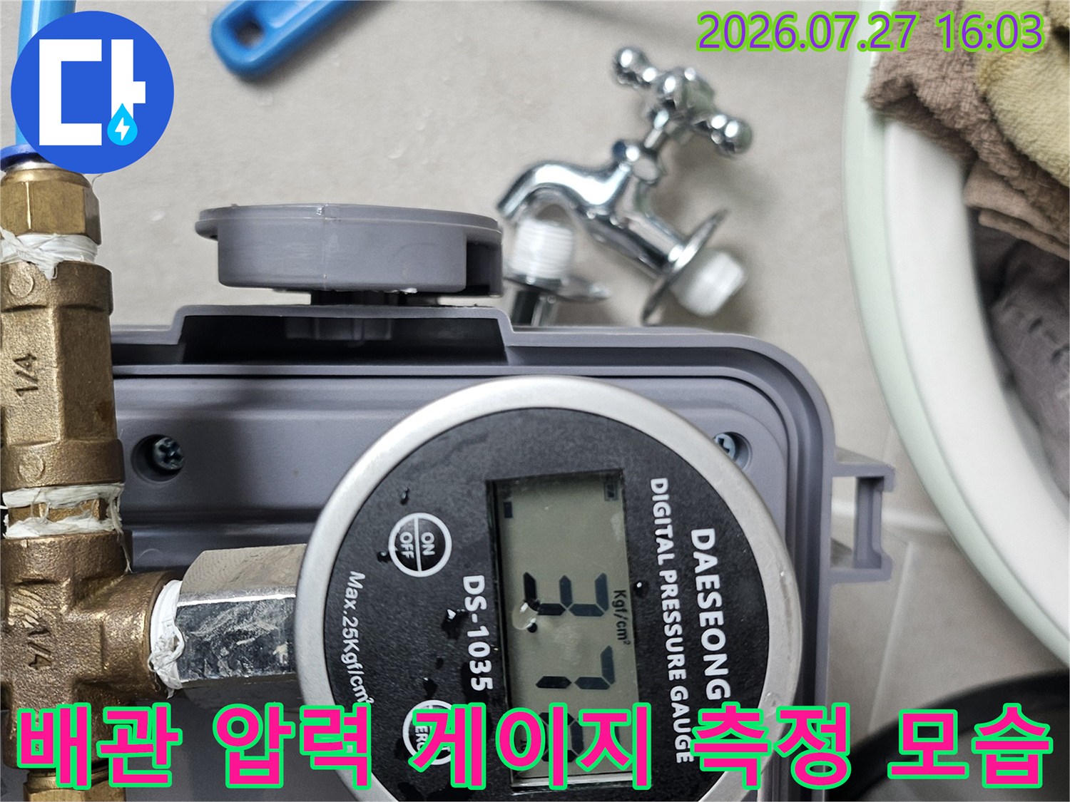 황동 연결 부품과 파란색 호스가 디지털 압력계에 연결되어 수치를 표시하고 있는 상태