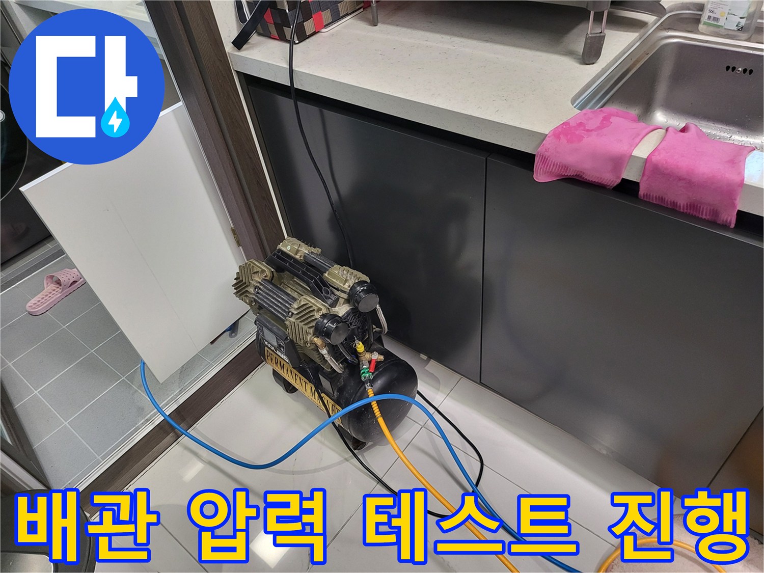 주방 싱크대 아래 배치된-누수 진단용 공압 장비와 호스 연결부