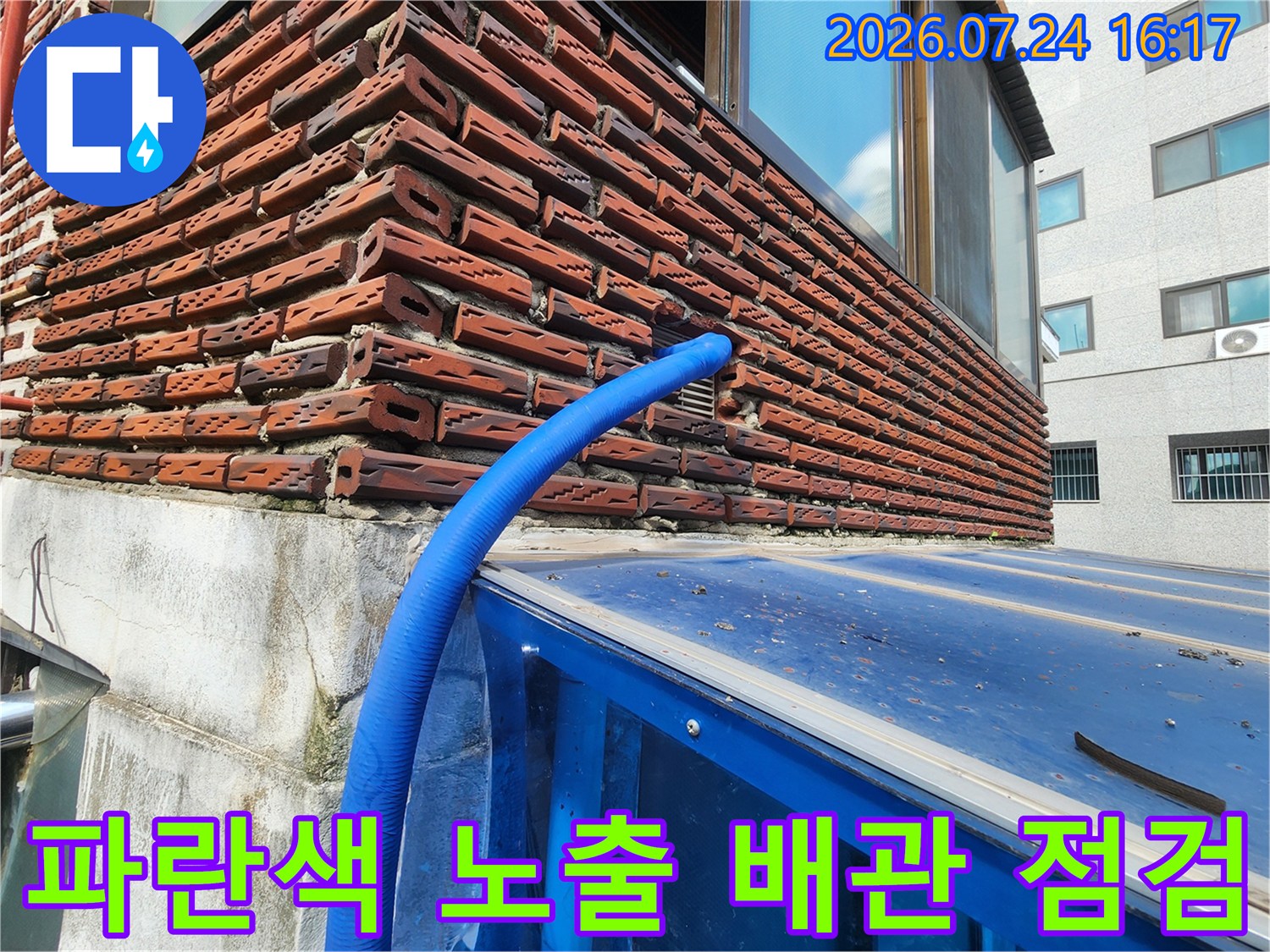 노출된 파란색 배관과 벽돌 외벽의 접촉 부위를 조사하는 현장