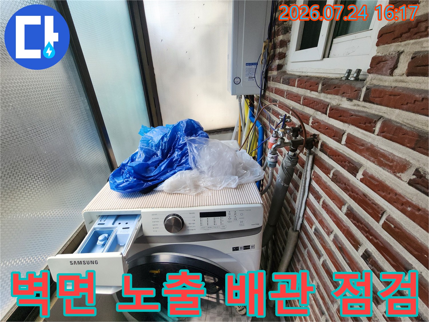 붉은 벽돌과 세탁기가 있는 공간에서 수도 및 가스용 배관을 확인하는 장면