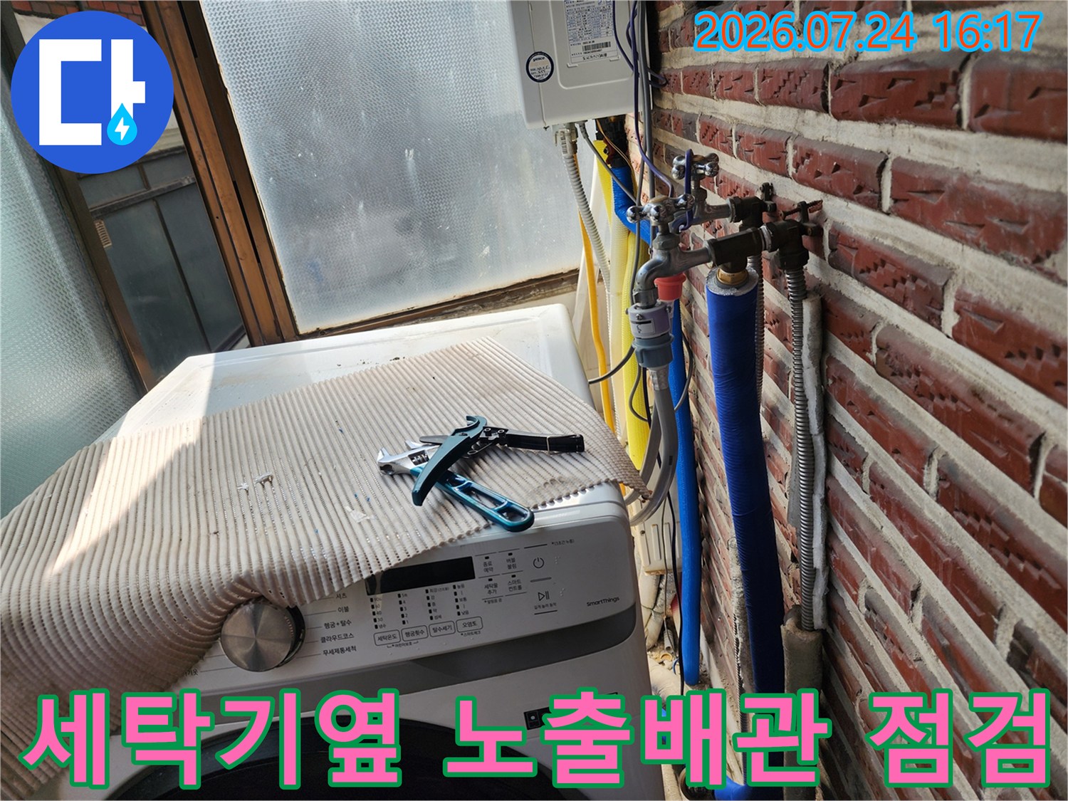 세탁기 옆에 위치한 파란색 보온재 배관과 밸브를 점검하는 모습